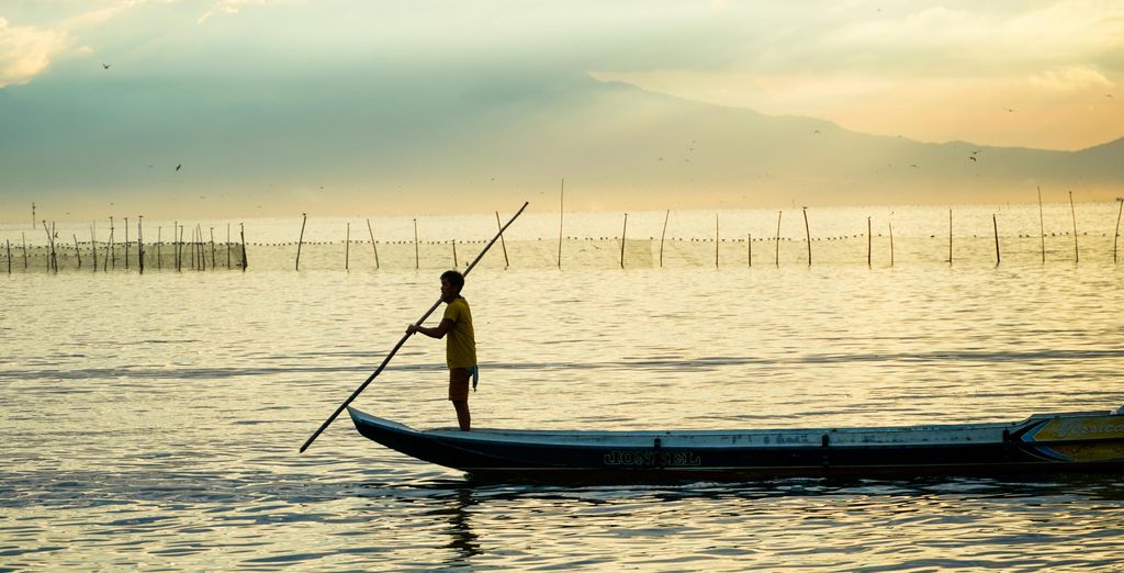 Pêcheur debout sur sa pirogue au coucher du soleil, aux Philippines