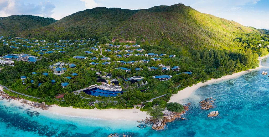 Baie seychelloise vue du ciel, hôtel niché dans la végétation au pied des collines de granit